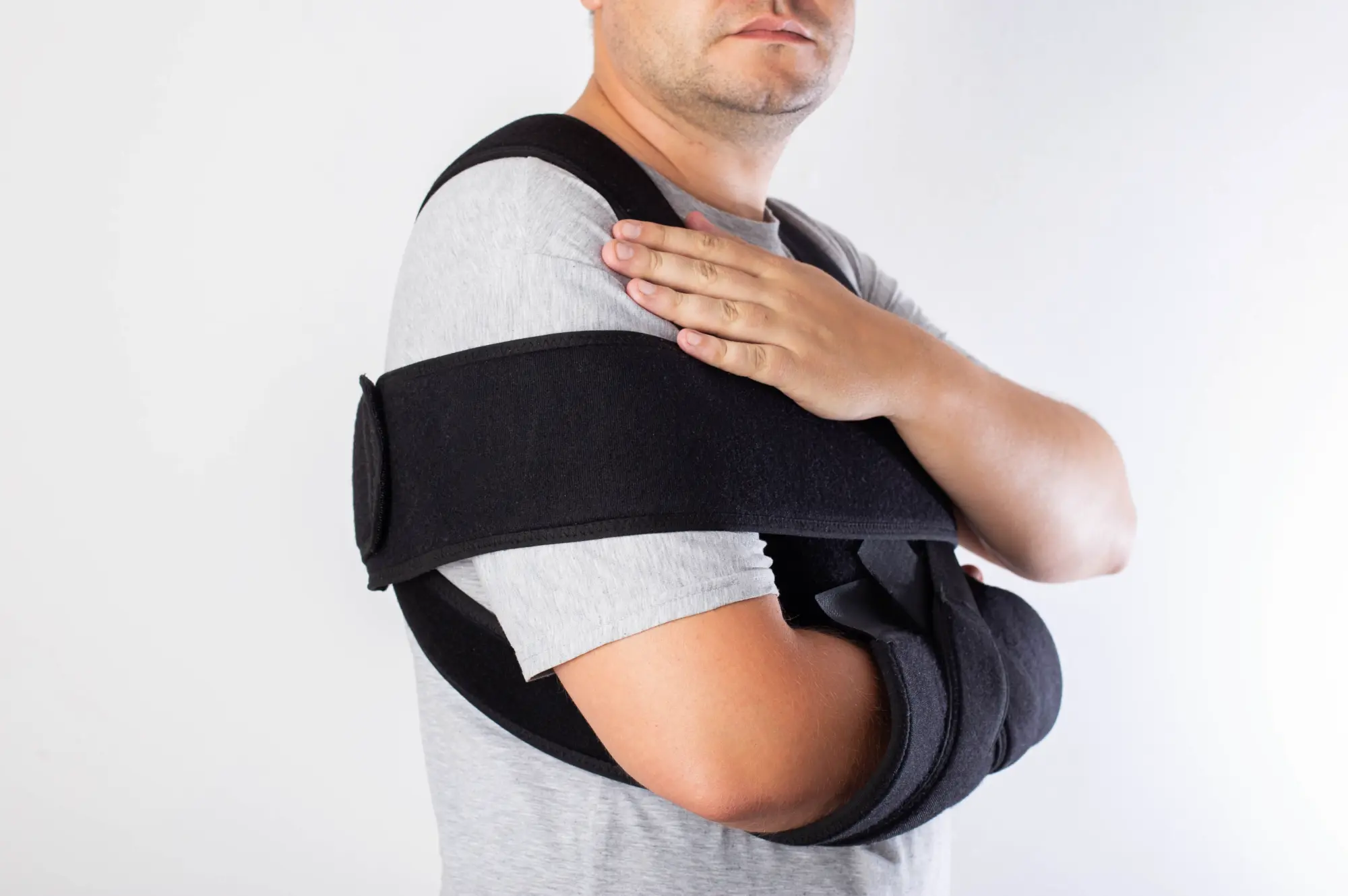 patient in a sling, with their arm indicating to their injured shoulder